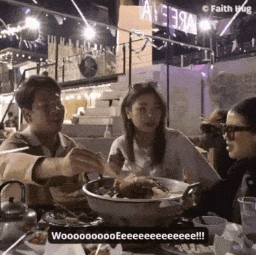 a group of people sitting at a table with a sign that says ay3e3a