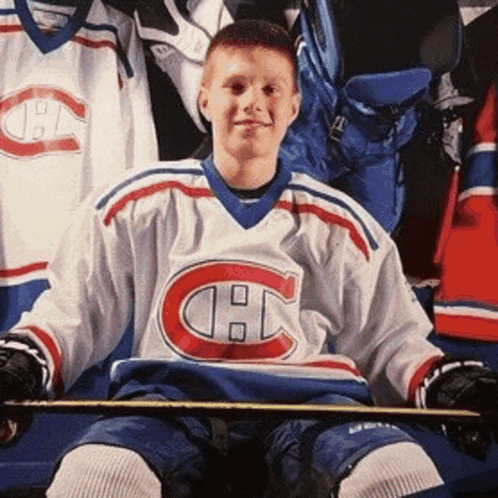 a boy in a canadiens jersey sits in the stands