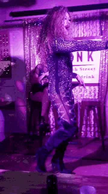 a woman is dancing in front of a sign that says ' nk ' on it