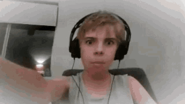 a young boy wearing headphones is making a funny face while sitting in a chair .