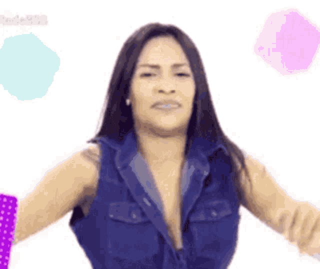 a woman in a blue denim vest is dancing with her arms outstretched
