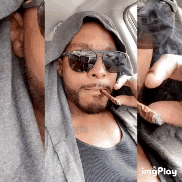 a man wearing sunglasses is smoking a cigar in a car with a hoodie on