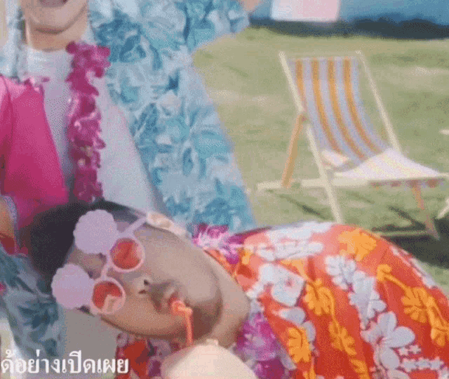 a man wearing sunglasses and a lei is laying on the ground