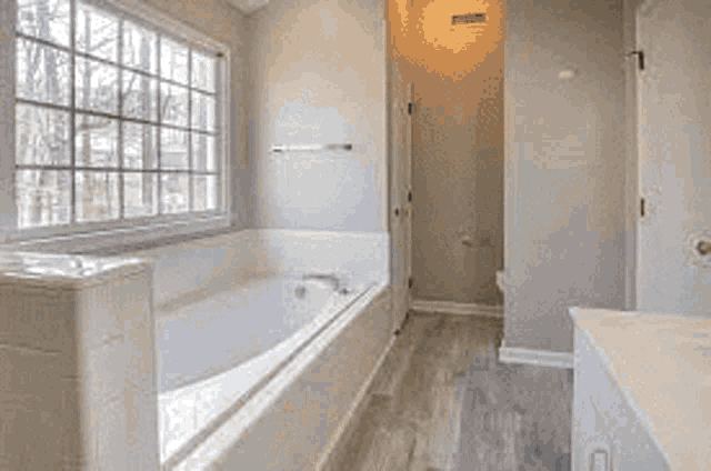 a bathroom with a tub , sink and window .