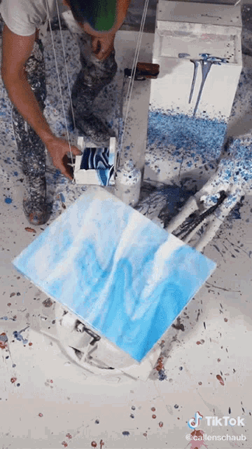 a man is painting a blue and white painting with a tiktok watermark on the bottom right