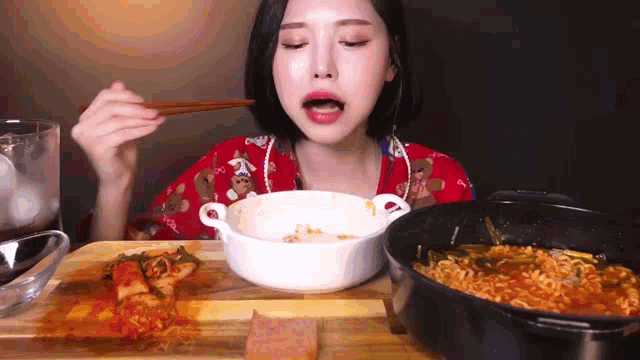 a woman is eating food with chopsticks and a bowl of noodles