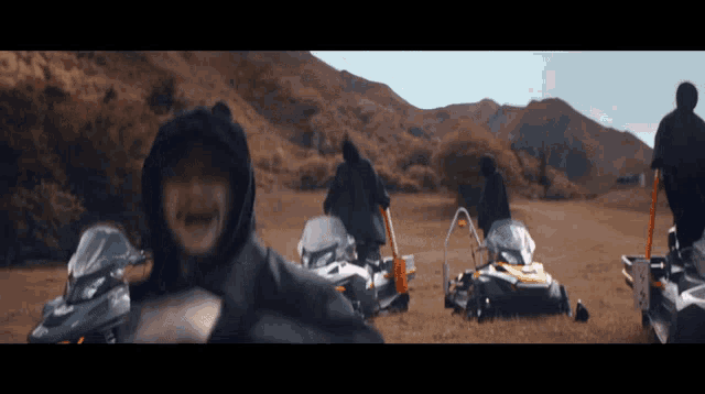 a man in a black hooded jacket is riding a snowmobile