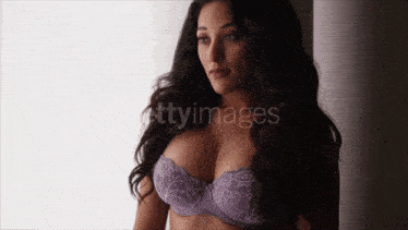 a woman wearing a purple bra is standing in front of a window