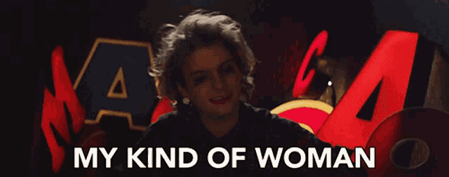a woman says " my kind of woman " in front of a red sign
