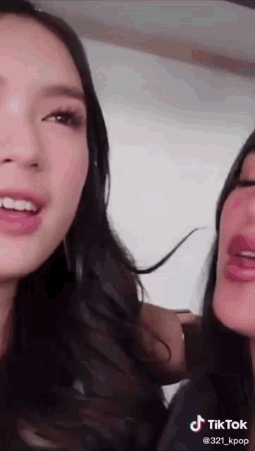 two women are looking at the camera and one has a tiktok watermark on her face