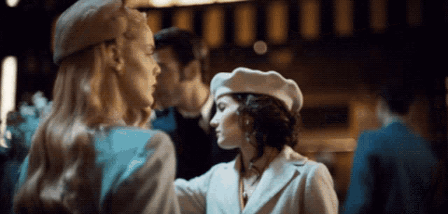 a woman wearing a white beret is talking to another woman