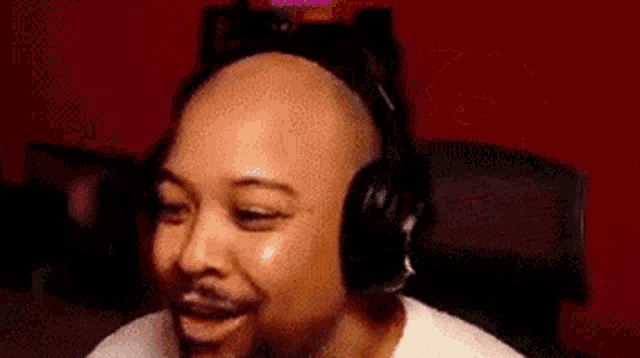 a bald man wearing headphones is smiling in a room .