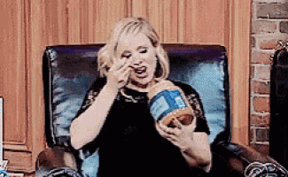 a woman is sitting in a chair with a jar of peanut butter in her hand .