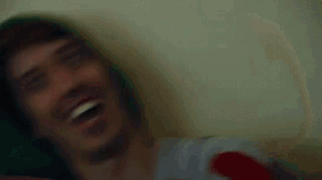 a man wearing a green hoodie is smiling and making a funny face .