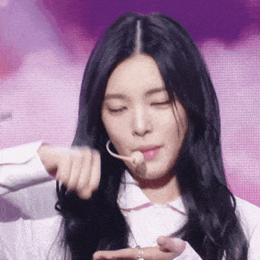 a girl with long black hair is holding a microphone in her mouth