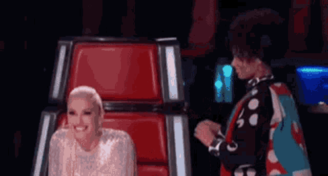 a woman is sitting in a chair next to another woman on a stage .