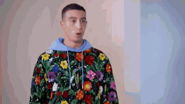 a man wearing a floral sweater and a blue hoodie is making a surprised face .