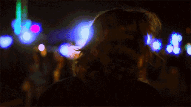 a close up of a woman 's face in front of a blurry background of lights .