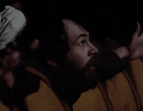 a man with a beard says " kako montira " while sitting in a dark room
