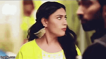 a man and a woman are looking at each other . the woman is wearing a yellow jacket and earrings .