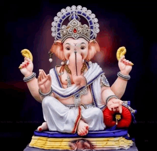 a statue of ganesha with a crown on his head is sitting on a pillow