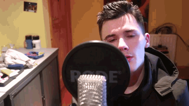 a man singing into a rode microphone in a kitchen