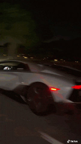 a car is driving down a highway at night and the rear view mirror is visible
