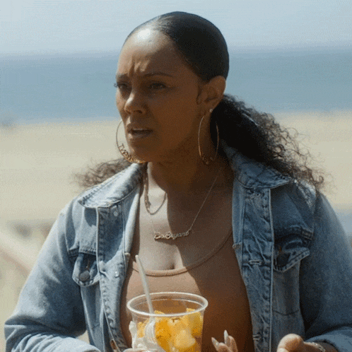 a woman wearing a necklace that says ' carolina ' on it holds a cup of food