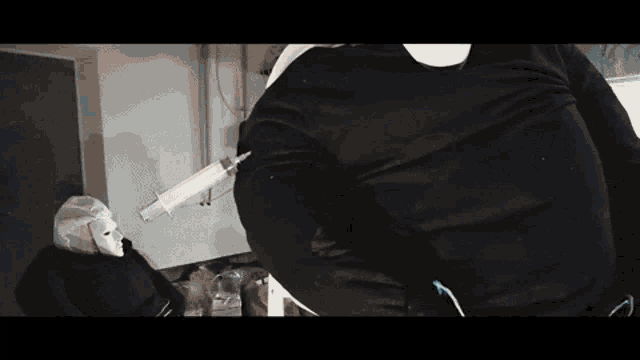 a man in a black shirt is holding a syringe in his hand