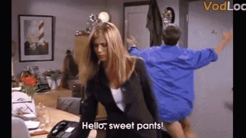 a woman in a suit is standing in front of a man in a blue shirt and says hello sweet pants