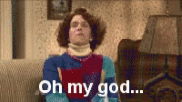 a woman with curly hair is sitting on a couch and says oh my god .