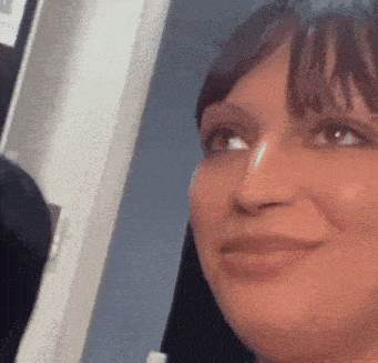 a woman is smiling and looking at the camera while standing in front of a mirror .