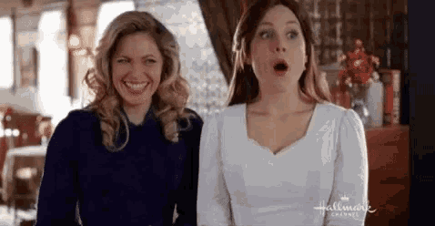 two women are standing next to each other with their mouths open in a room .