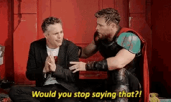 two men are sitting next to each other and talking to each other .