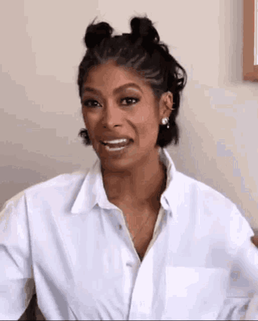 a woman wearing a white shirt and earrings is smiling .