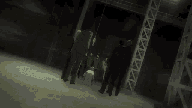 a group of men are standing in a dark room with a light hanging from the ceiling
