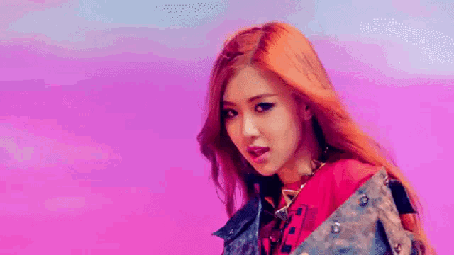 a woman with red hair is wearing a denim jacket and a necklace .