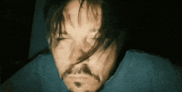 a man with a beard is laying down with his eyes closed