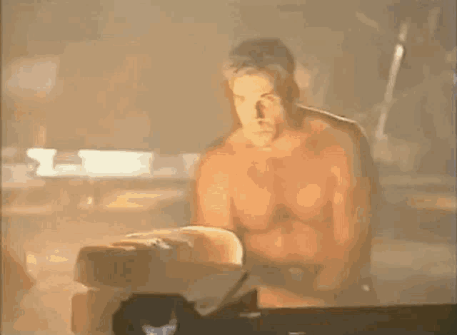 a shirtless man is standing in a dark room holding a piece of paper .