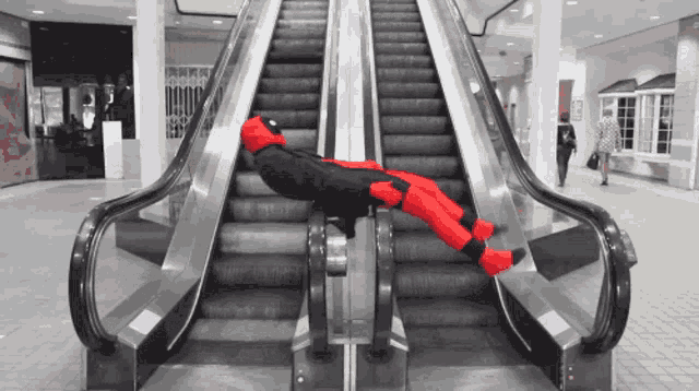 a person in a deadpool costume laying on an escalator