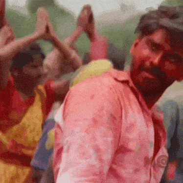 a man with red paint on his face is dancing with a crowd of people .