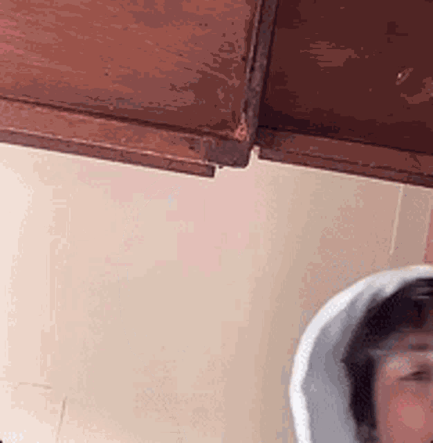 a person wearing a white hat is standing under a wooden ceiling in a room .