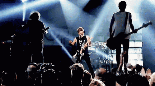 a man playing a guitar on a stage in front of a crowd that is watching
