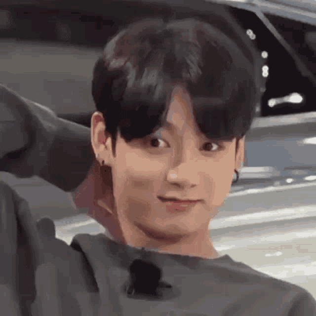 a close up of a young man making a funny face while standing next to a car .