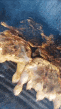 a chicken is being cooked on a grill with smoke coming out of it