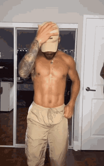 a shirtless man wearing a hat with the word lacoste on it