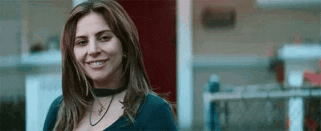 a woman wearing a choker and a blue shirt is smiling in front of a red door .