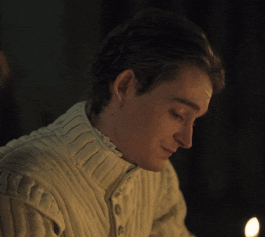 a man wearing a white sweater is looking down at something