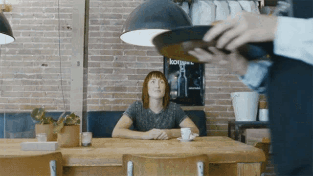 a woman sits at a table in front of a sign that says kong