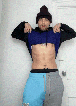 a man wearing a beanie is taking off his shirt and shorts